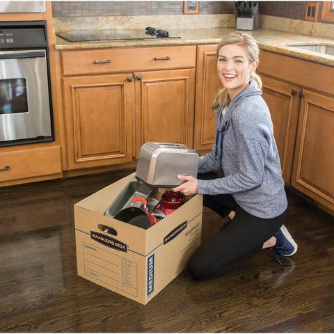 Woman packing kitchen items into Solid Gear Medium Moving Boxes 20 Pack With Tapeless Assembly And Reinforced Carry Handles.