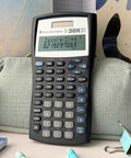 Legit Game Changing Scientific Calculator Featuring Two Line Display Advanced Statistics And Quick Fraction Conversions on a desk.