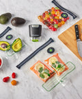 Reusable Quart Vacuum Zipper Bags, 10 Count, BPA Free, Microwave Safe, with assorted foods on a kitchen counter