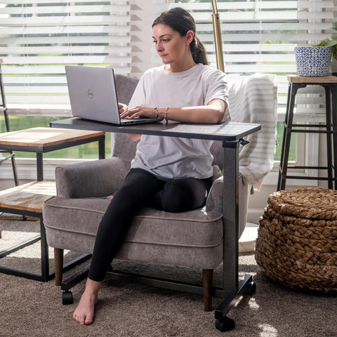 Person using Rolling Overbed Table With Wheels For Bedside, Sofa Or Recliner Adjustable Height Laptop Desk next to a chair.