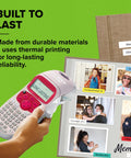 Pink Handheld Label Maker For Home And Office, Lets You Create Quick, Stylish Labels With ABC Keyboard, 13-Character LCD shown in use next to a photo album.