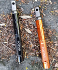2 Pack Ferro Rod Fire Starter With Replaceable Flint in orange and black on ground, aluminum body, for camping hiking emergency.