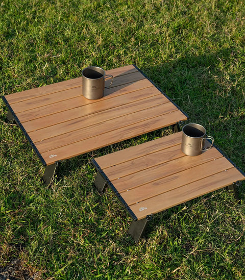 Ultralight Compact Mini Beach Picnic Folding Aluminum Table With Carry Bag Nature Finish Flat Surface Durable Hinges Two Size Options S And M For Sand And Picnics with two sizes shown on grass, each holding a mug.
