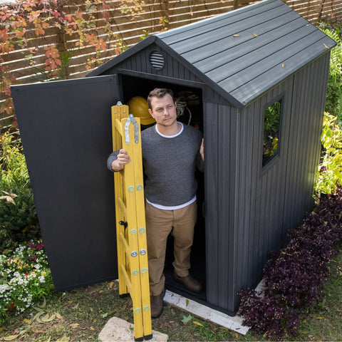 Lockable Resin Outdoor Storage Shed Graphite Gray Four By Six Feet Weather Resistant Patio Garden Tool Organizer with a man standing at the door.