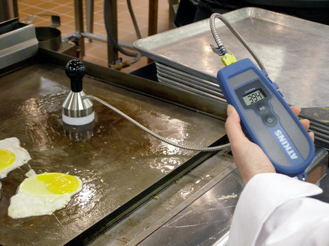 Weighted Griddle Surface Thermocouple Probe Type K For Grills And Flat Tops Minus Forty To Five Hundred Degrees Fahrenheit Range Ultra Fast Two Second Read Time On Oiled Surfaces 2.5 Inch Diameter Flexible Armor With PTFE Coated Shaft in use on a griddle cooking eggs.