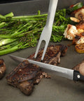 Chef slicing steak on flat top grill with 24 Piece Griddle Tool Set With Storage Tote Stainless Steel Flat Top Grill Accessories