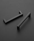 Square Bar Cabinet Handles Matte Black Set Of 10 With 5 Inch Hole Center And 5-1/2 Inch Overall Length laying on a dark surface