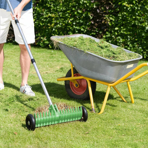 Thatch Rake For Lawn 15 Inch Dethatcher With Smooth Rolling Wheels Adjustable 0 To 15 Degrees 38 To 68 Inch Handle Heavy Duty Thatching Rake For Quick Dead Grass Cleanup And Yard Work Olive in use on grass with wheelbarrow