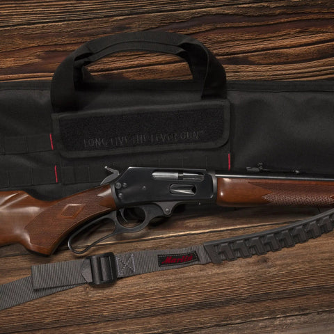 Baktrak Traction Web Rifle Sling With 36 Inch Length 500 Pound Rated Swivels Slim Non Slip Pad next to rifle and gun bag.