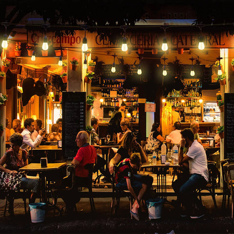 Outdoor cafe scene at night with 48 Foot LED Color Changing String Lights With Remote hanging above tables and patrons.