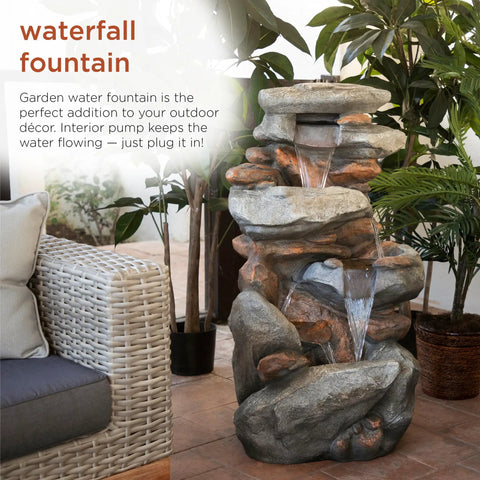 40-Inch Four Tier Rock Floor Fountain With Cascading Water And White LED Lights in a natural garden setting.
