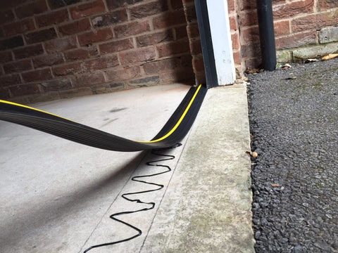 Close-up of Beefed Up Garage Door Threshold Seal Kit with adhesive being applied to 10 ft 6 in door threshold, weatherproof seal visible
