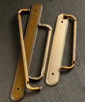 Game Changing Antique Brass Cabinet Pulls and Drawer Handles, 5 Inch Hole Center Zinc Alloy Kitchen Hardware With Vintage Backplate and Spacer, Rock Solid Corrosion Resistant Shine Makes Assembly As Easy As Pie in This 2 Pack to Spice Up Your Kitchen - close-up of two antique brass handles on a wooden surface.