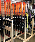 Badass Five Pack Ski Wall Hangers Securely Grip Every Alpine Board From Rockers To Racers And Kids Patented Design Saves Tip Wear While Keeping Your Garage Storage Dead Slick, showcasing multiple skis on wooden rack.