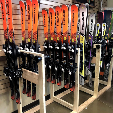 Badass Five Pack Ski Wall Hangers Securely Grip Every Alpine Board From Rockers To Racers And Kids Patented Design Saves Tip Wear While Keeping Your Garage Storage Dead Slick, showcasing multiple skis on wooden rack.