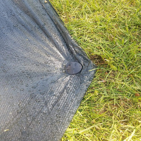 Black heavy duty outdoor stake securing black tarp on grass, part of 30 Pack 4.3 Inch Plastic Stakes Anchors Beefy Rustproof Thick Resin For Holding Down Landscape Fabric Lawn Edging Tents Game Nets And Rain Tarps Black Heavy Duty Outdoor Stakes Set