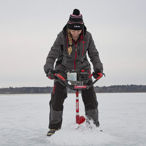 Woman using Rock Solid Pistol Bit Adapter For Auger Powerheads on ice with Eskimo auger, wearing winter gear.