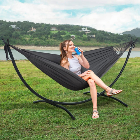 Heavy Duty Hammock Stand With Portable Foldable Patio Hammock For Backyard Or Deck, Sturdy Steel Frame With Non Slip Feet, Supports Up To 475 Lbs, Fits 2 To 3 People, Dark Gray Outdoor Lounging featuring a woman relaxing outdoors.