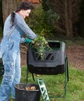 Person using Mr Spin Compost Tumbler With Dual Chamber Design 160 Liter 43 Gallon Capacity Two Leg Stand Green And Black.
