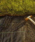 100 Pack 6 Inch 11 Gauge Heavy Duty U Shaped Garden Staples Ground Stakes For Anchoring Landscape Fabric Spikes Pins Pegs Pro Grade Lawn Landscaping Tools, shown on landscape fabric near grass.