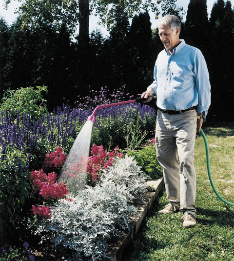 Man watering a flower bed with Sunrise Soft Rain Watering Spray Wand 30 Inch With Shut Off Valve Berry Color Gentle Full Flow Spray