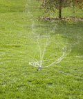 Heavy Duty Spinning Sprinkler With Wheeled Base For 360 Degree Coverage in operation on lawn delivering gentle rain-like spray