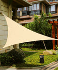 Sand Color 14 Ft Triangle Sun Shade Sail Canopy for Garden Deck Pool Patio Pergola Backyard Sandbox Breathable UV Blocking 90 Percent Sun Shade with Reinforced Corners and Steel Fittings for Quick Set Up installed in a garden area.