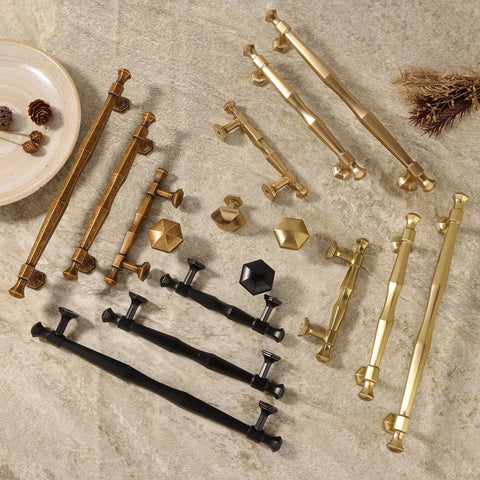 Variety of zinc alloy cabinet pulls in antique brass, black, and gold finishes on stone surface, featuring different designs and sizes.