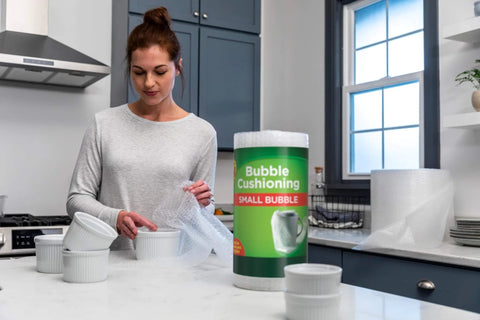 Woman using Bubble Wrap Protective Packaging 12 Inch Wide 30 Foot Roll Clear Bubble Cushions For Delicate Items Reusable Recyclable on dishes.