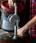 Person operating Fill-Rite SD62 Hand Pump Rotary 2-Vane Curved Spout on a drum for fluid transfer in an industrial setting.