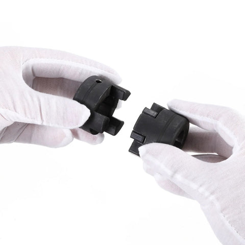 Close-up of black plastic L-jaw coupling halves from a 3-piece set with Buna-N rubber spider, held by gloved hands