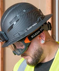 Construction worker wearing corded reusable earplugs with 25dB NRR in bright orange case for loud environments and safe fit.