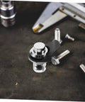 Close-up of chrome push-button latch with black mounting arm for cabinets or boats.