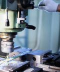 Person operating milling machine with adjustable screw jack set for precise leveling, supporting heavy equipment.
