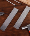 Two stainless steel wedges from Six Piece Stainless Steel Flange Wedge Set For Welding Lathe Machines 7x1.3in on a wooden surface.