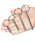 Hand holding four sets quarter inch diameter single ball quick release pins made from 316 stainless steel for marine hardware with lanyard.