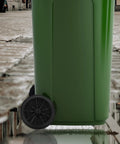 A green outdoor trash bin with installed 7-inch rubber wheels designed for easy transport on patios and driveways.