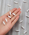 Hand holding white 40 Pieces Shutter Repair Pins, Plantation Shutter Fasteners Spring Loaded Replacement Repair Pins for window and cabinet slats.